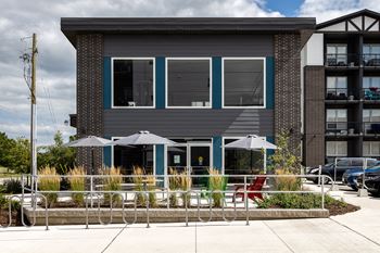 a building with blue windows and a patio with chairs and umbrellas